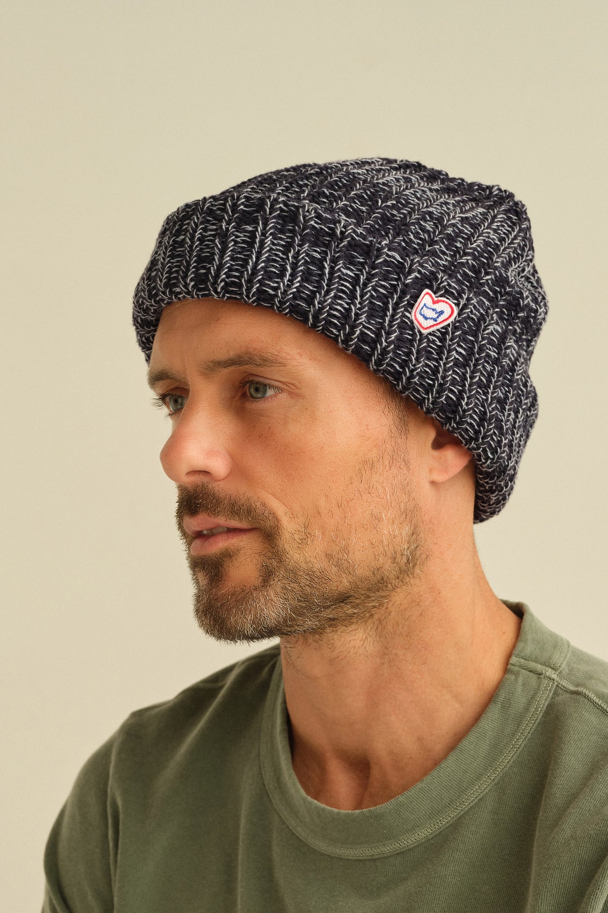 Dark heather knit beanie with red heart logo patch, close-up