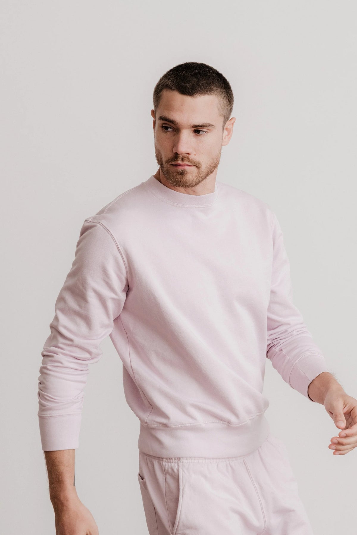 Light pink crewneck sweatshirt on model, long sleeves and ribbed hem visible