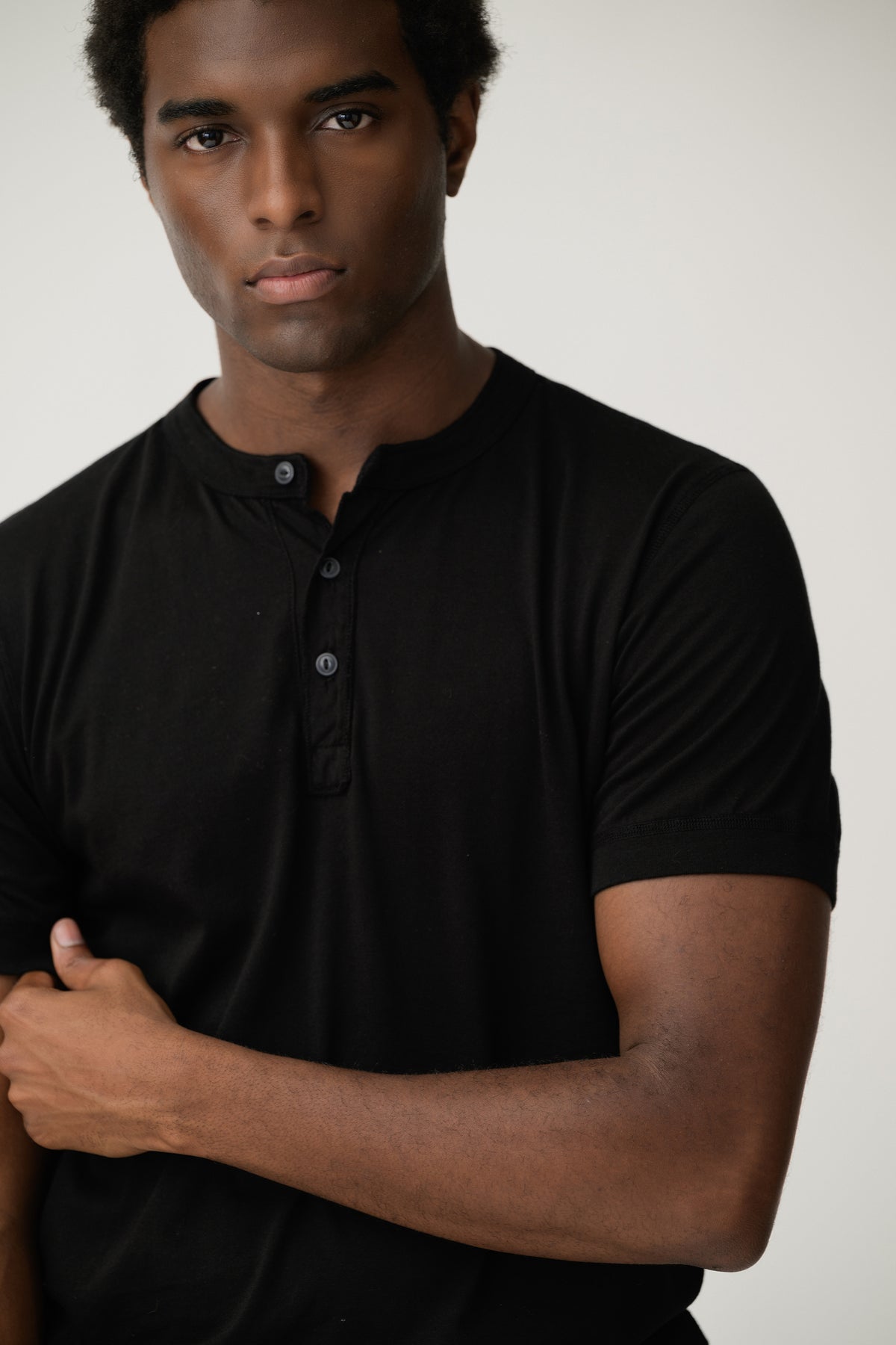 Black short-sleeve henley shirt close-up on model, V-neck button placket