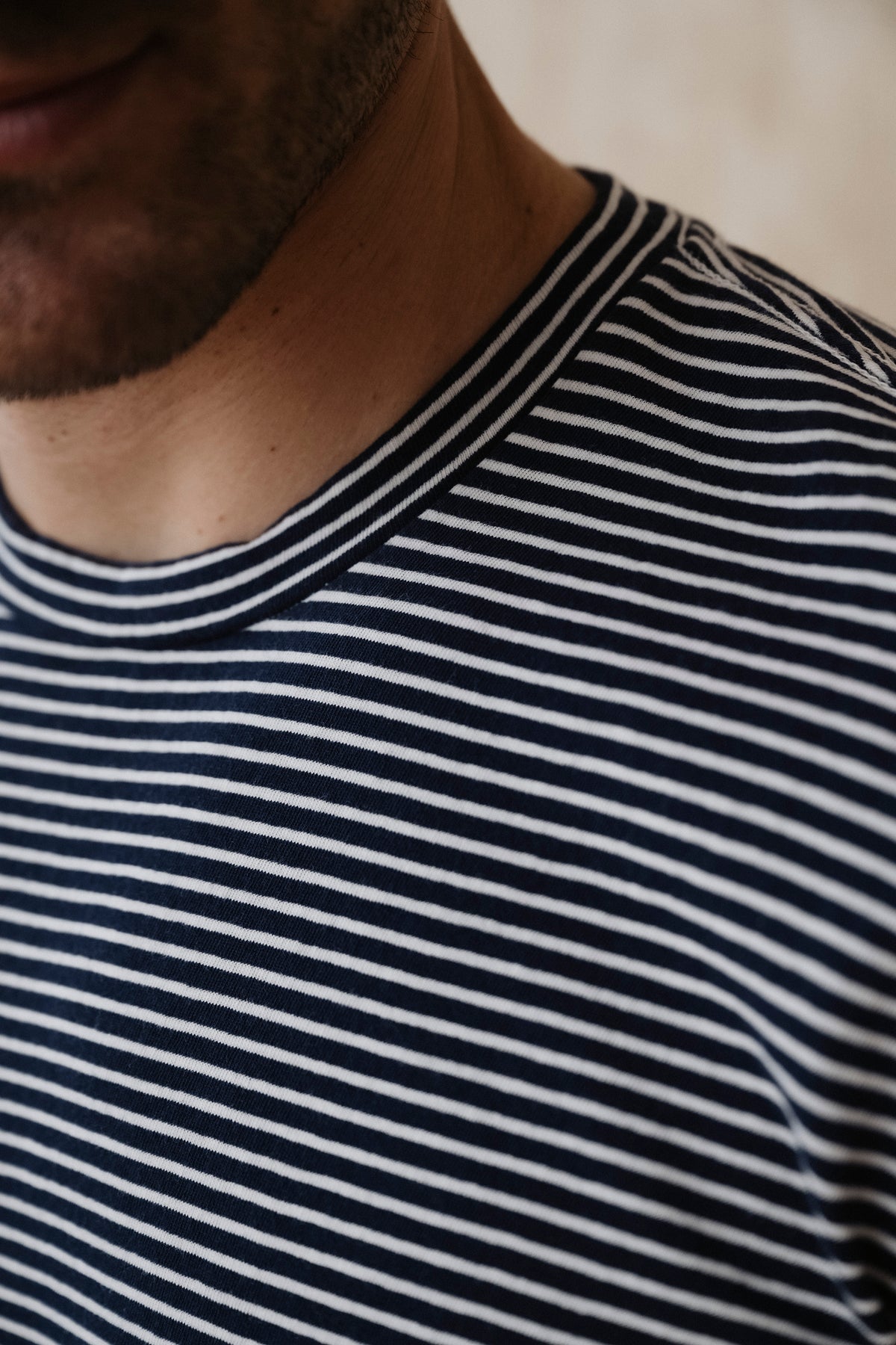 Close-up of striped crew-neck T-shirt collar, navy and white horizontal stripes