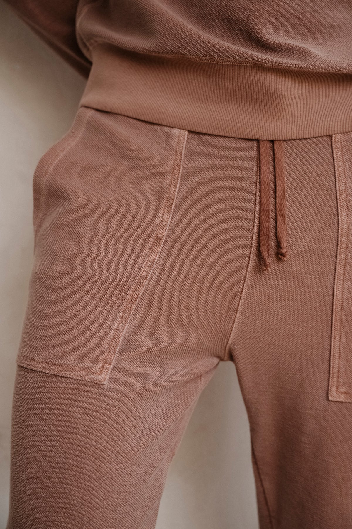 Rust terry sweat pants close-up of side seam, patch pocket, and drawcord