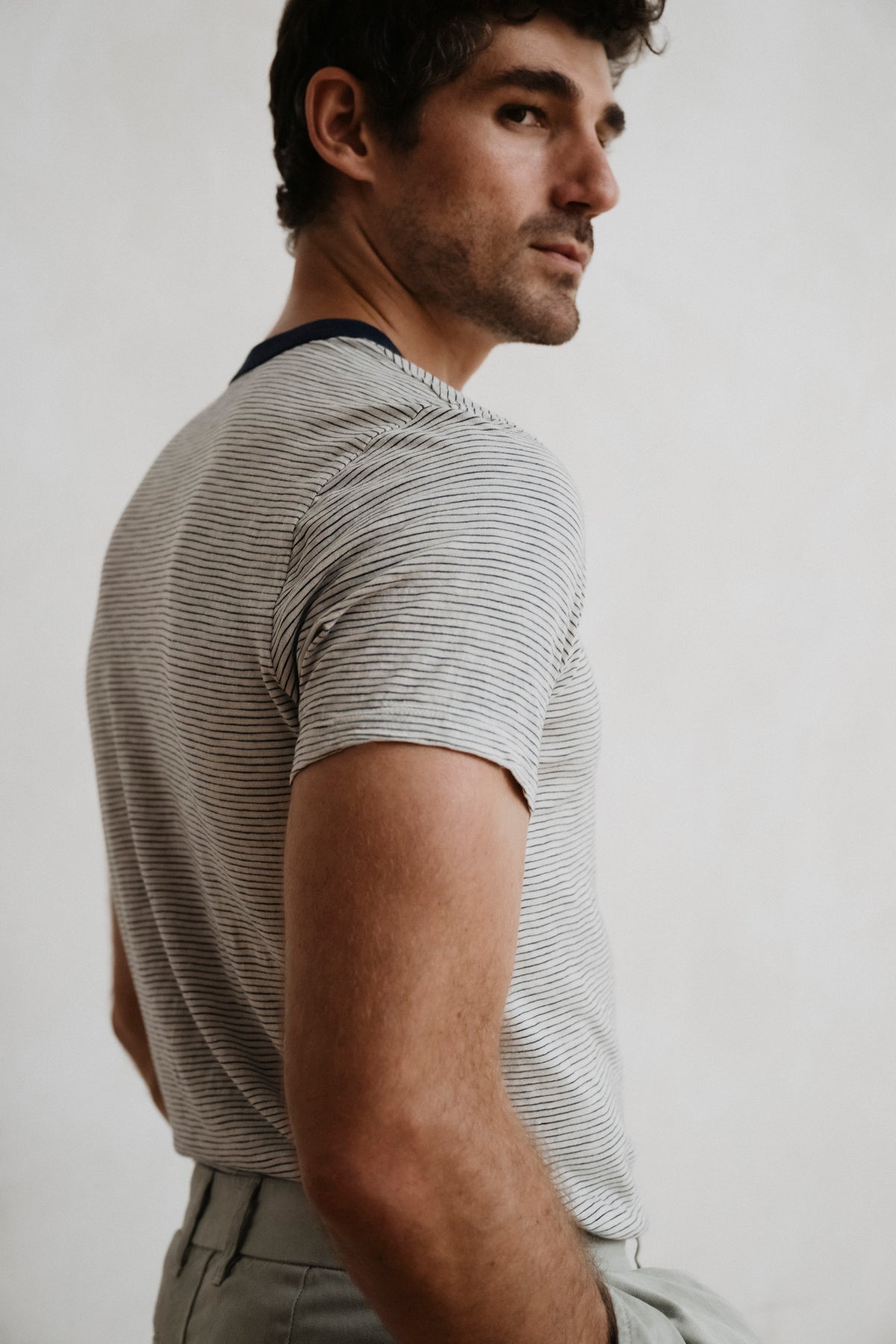 Side view of thin stripe ringer T-shirt in light gray with dark navy neck trim