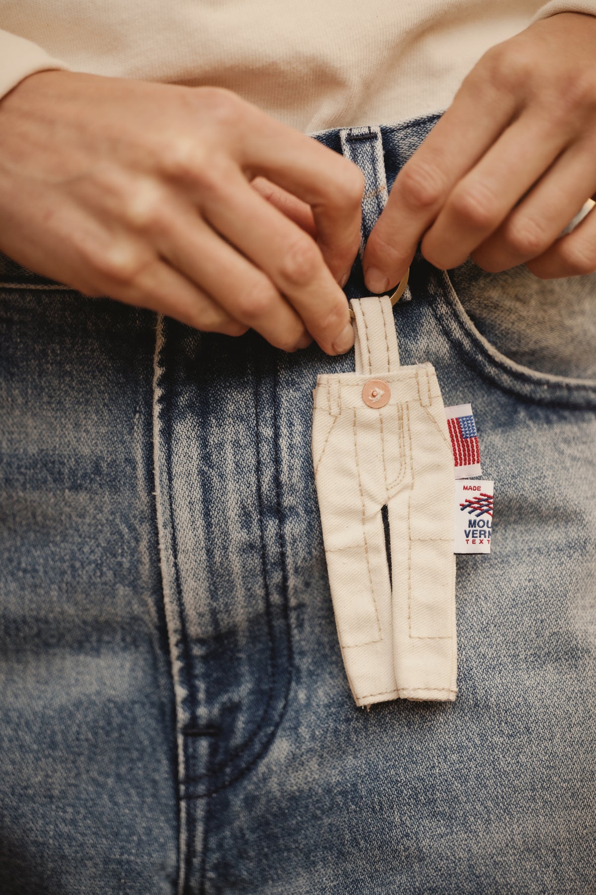 Dungaree key chain clipped to blue jeans, beige canvas overalls