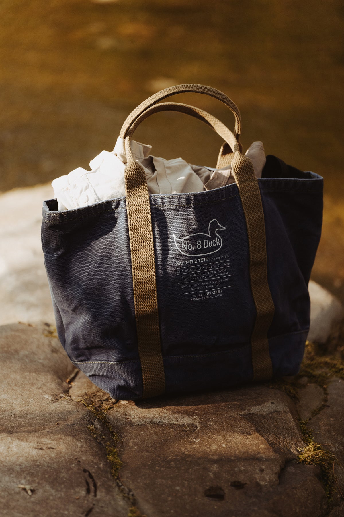 Dark tote bag with tan handles and front “No. 8 Duck” label