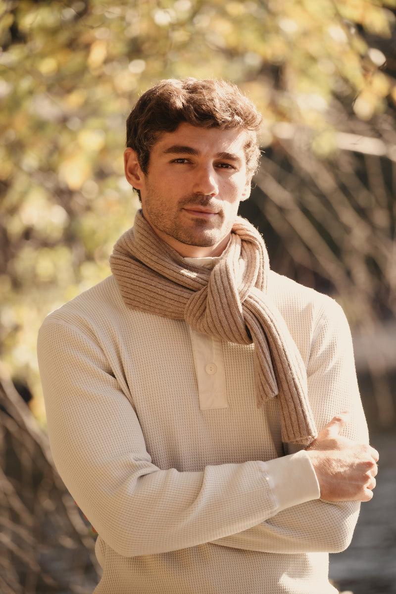 Light tan cashmere scarf wrapped around the neck with long folded ends.