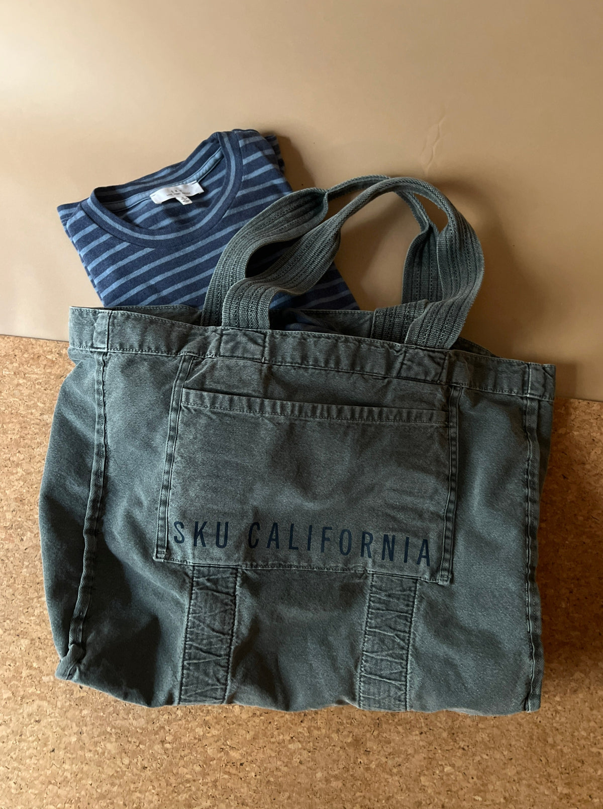Blue denim tote bag with logo patch and two handles, folded-front view