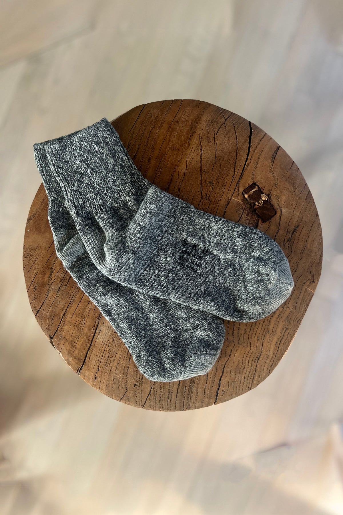 Pair of heather gray ankle socks with ribbed cuffs on wooden round display