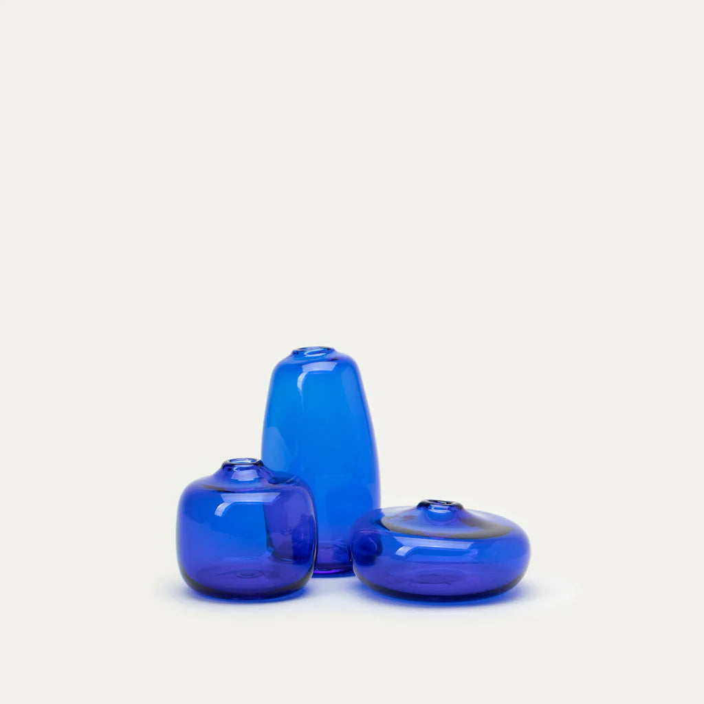 Three blue glass decorative vases: one tall cylinder and two short rounded vases