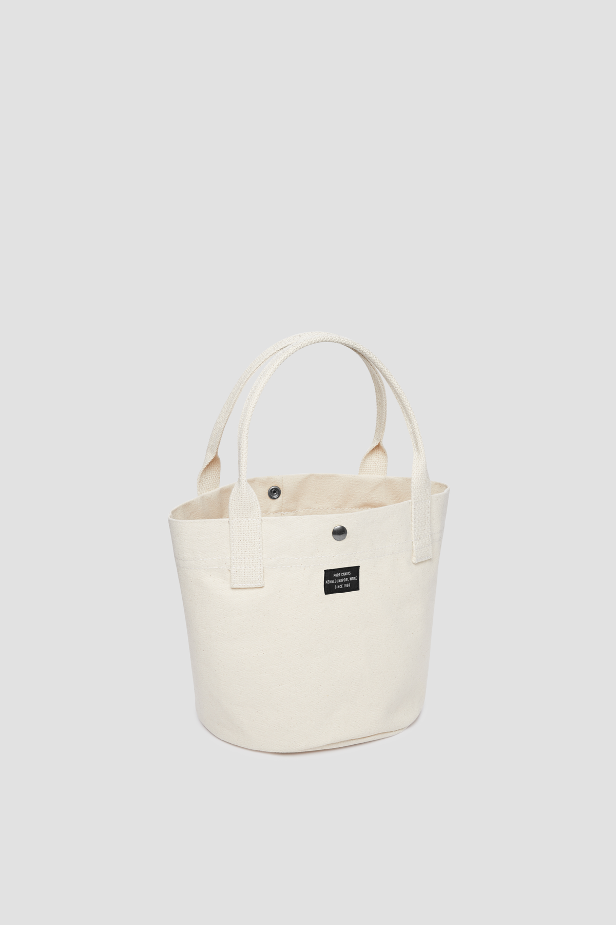 Round canvas tote bag in natural with short handles and front pocket