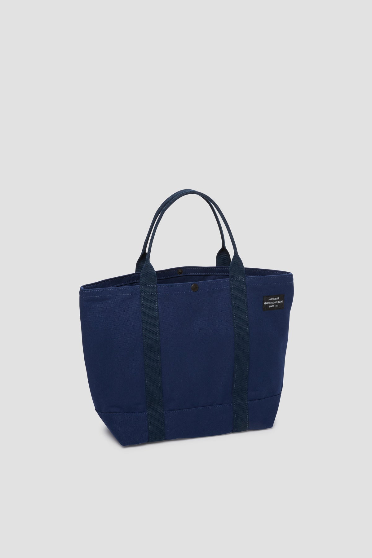Navy canvas tote bag with long handles and small front pocket detail