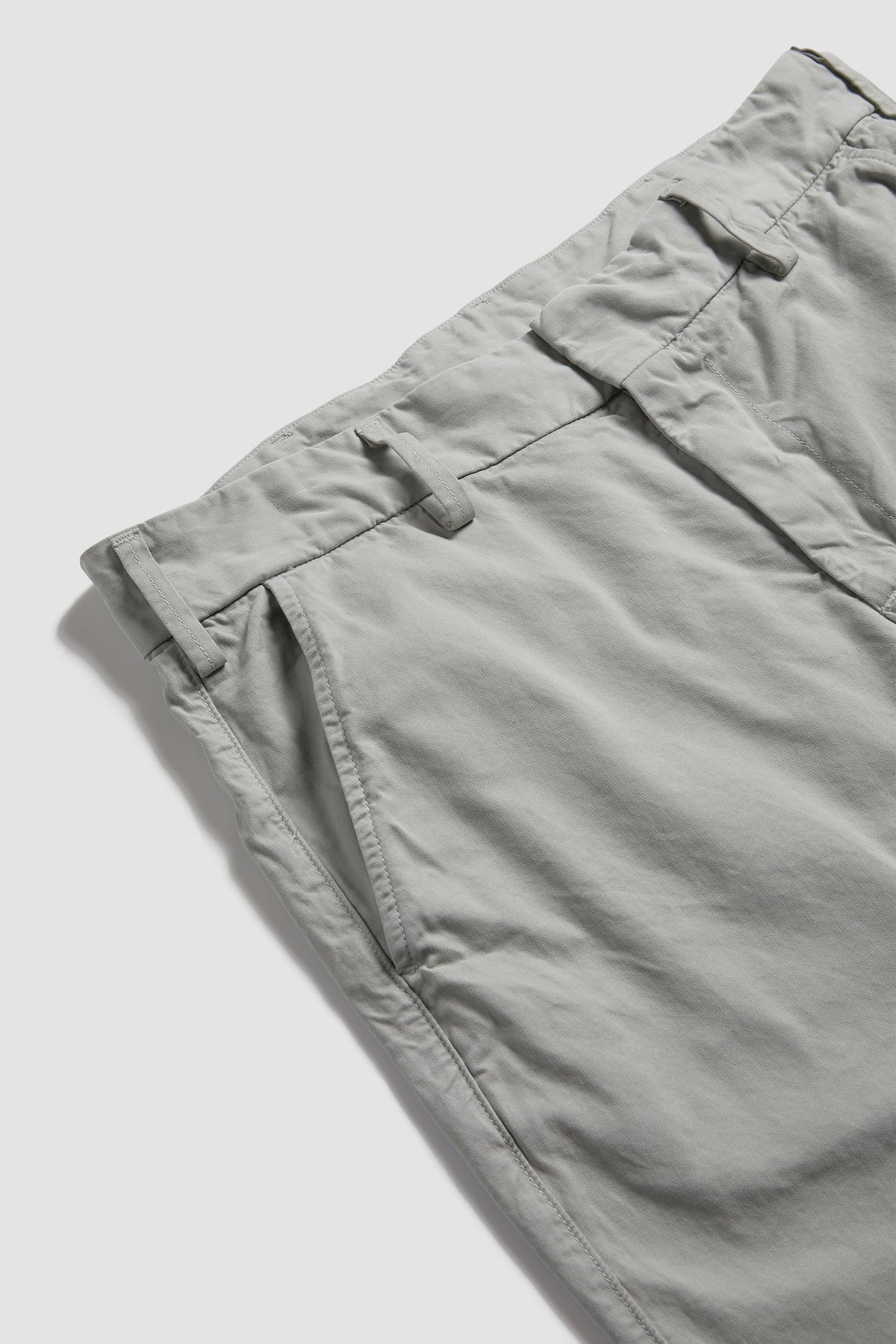 Light gray chino pants close-up of waistband and buttoned fly front