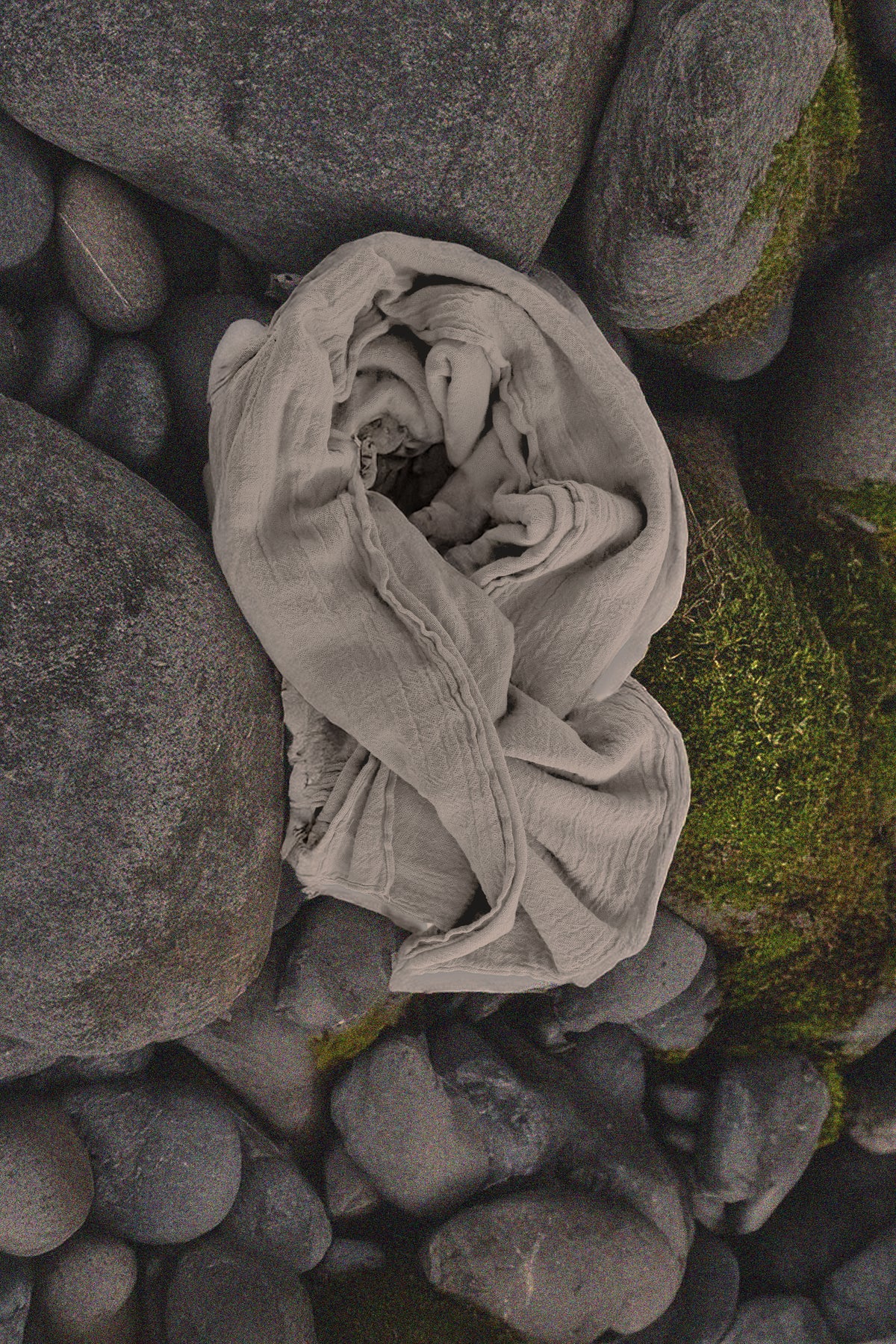 Folded gray cloth wrap throw with a rosette-like twist on textured rocks