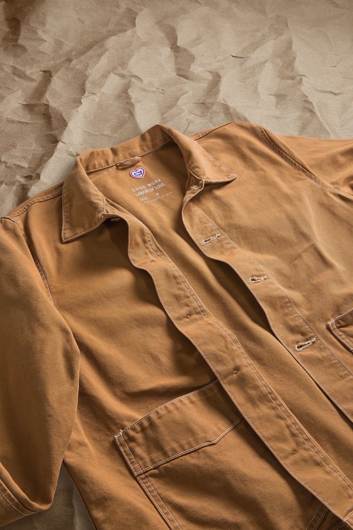 Brown canvas work jacket detail: collared neck, chest pocket flaps, button front