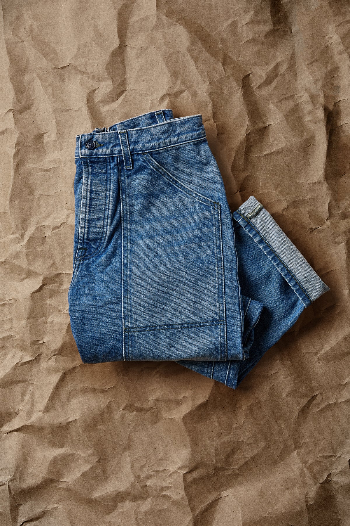Vintage indigo denim dungaree pants, folded flat with back patch pockets