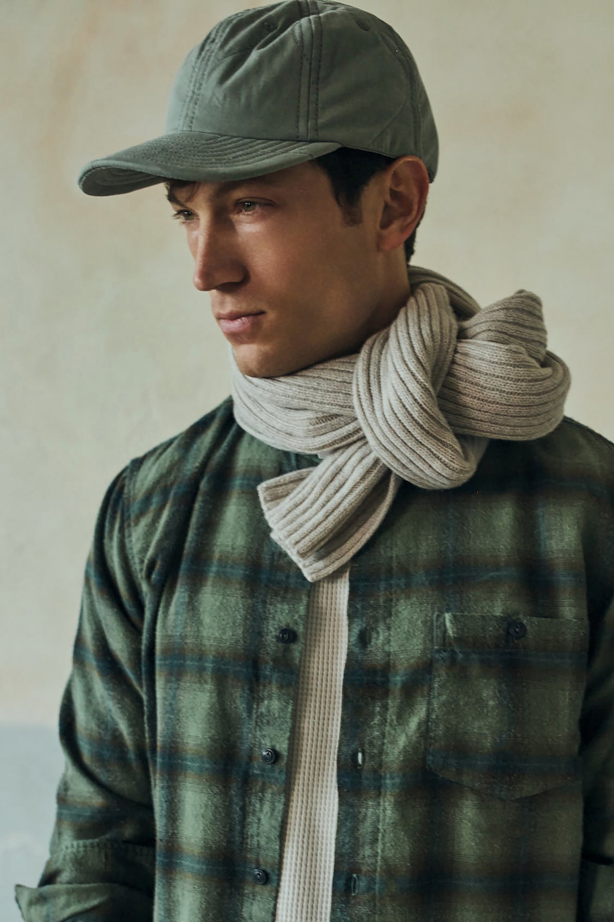 Rib-knit cashmere scarf in dark gray-green, draped around neck with folded ends.