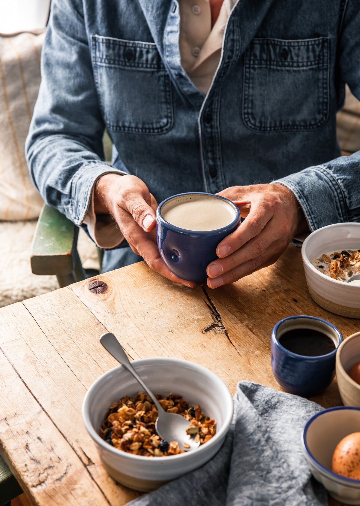 Maker Blue ceramic coffee mug, held in hands with light coffee inside