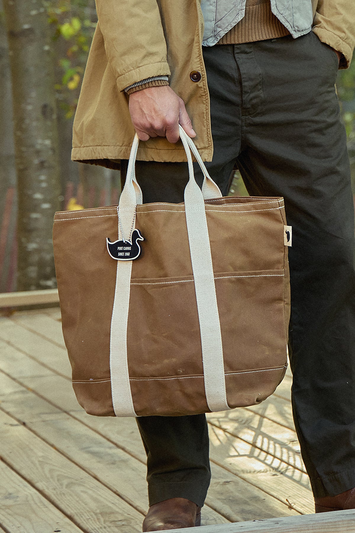Double utility wax tote with white straps, field brown canvas, front pocket detail.