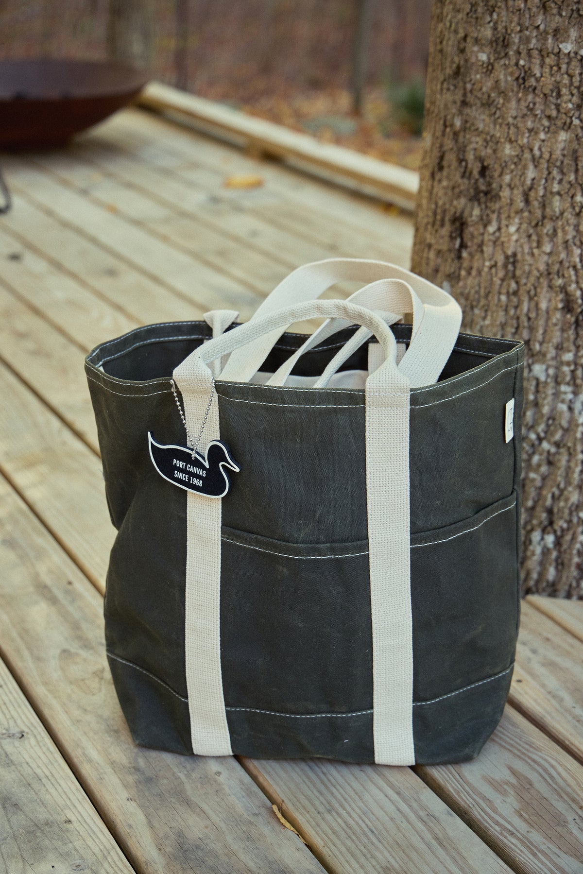 Double utility wax tote with white straps, dark navy canvas, side label patch.