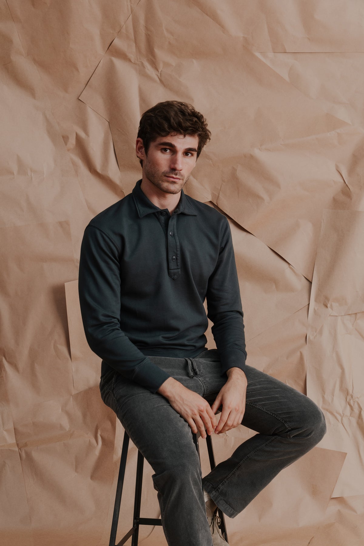 Dark green long-sleeve fleece polo shirt on model seated, collared neckline and buttons