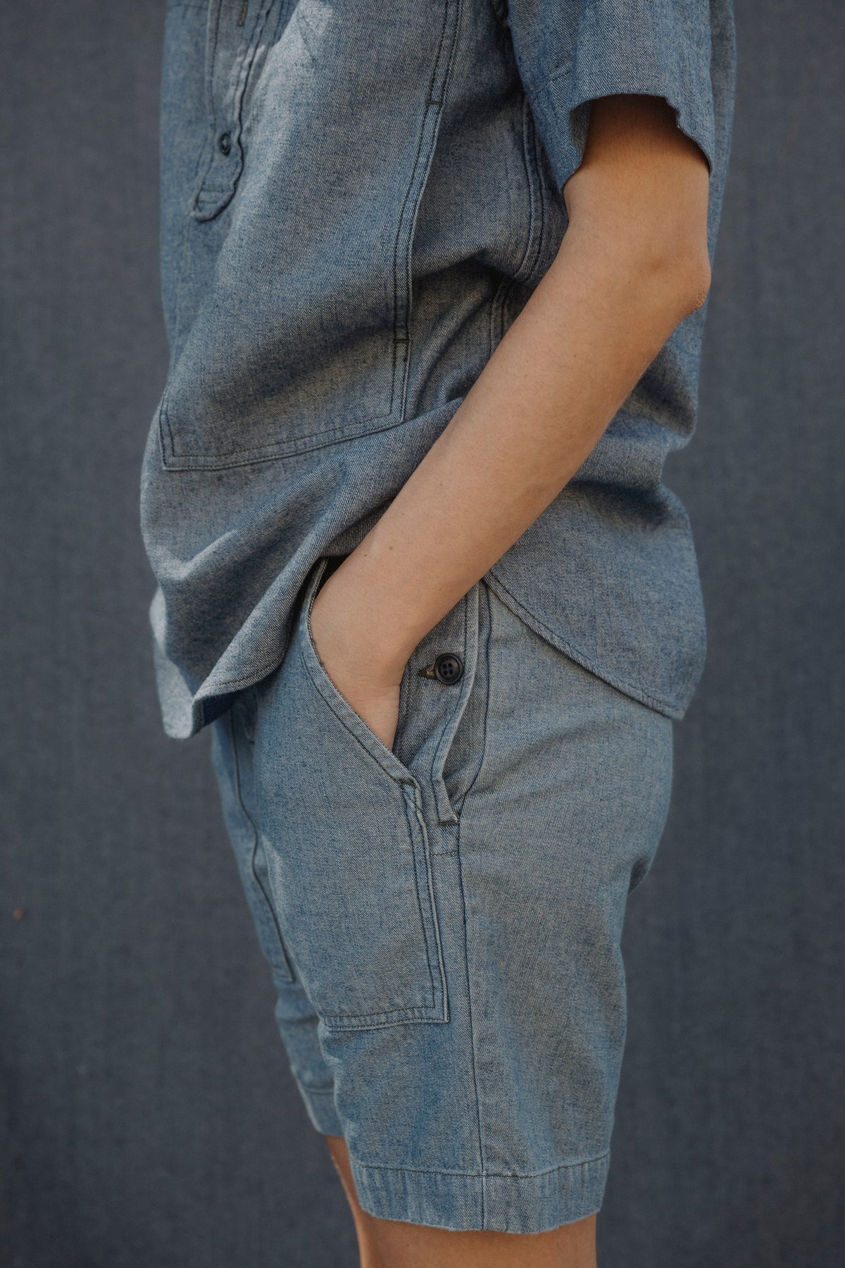 Light blue denim shorts close-up: side cargo pocket and buttoned fly