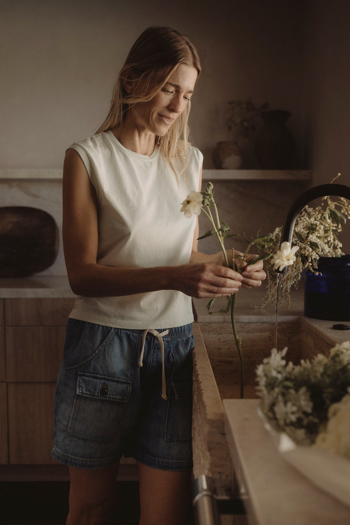 Denim drawstring fatigue shorts with patch pockets and stitched seams, worn mid-thigh