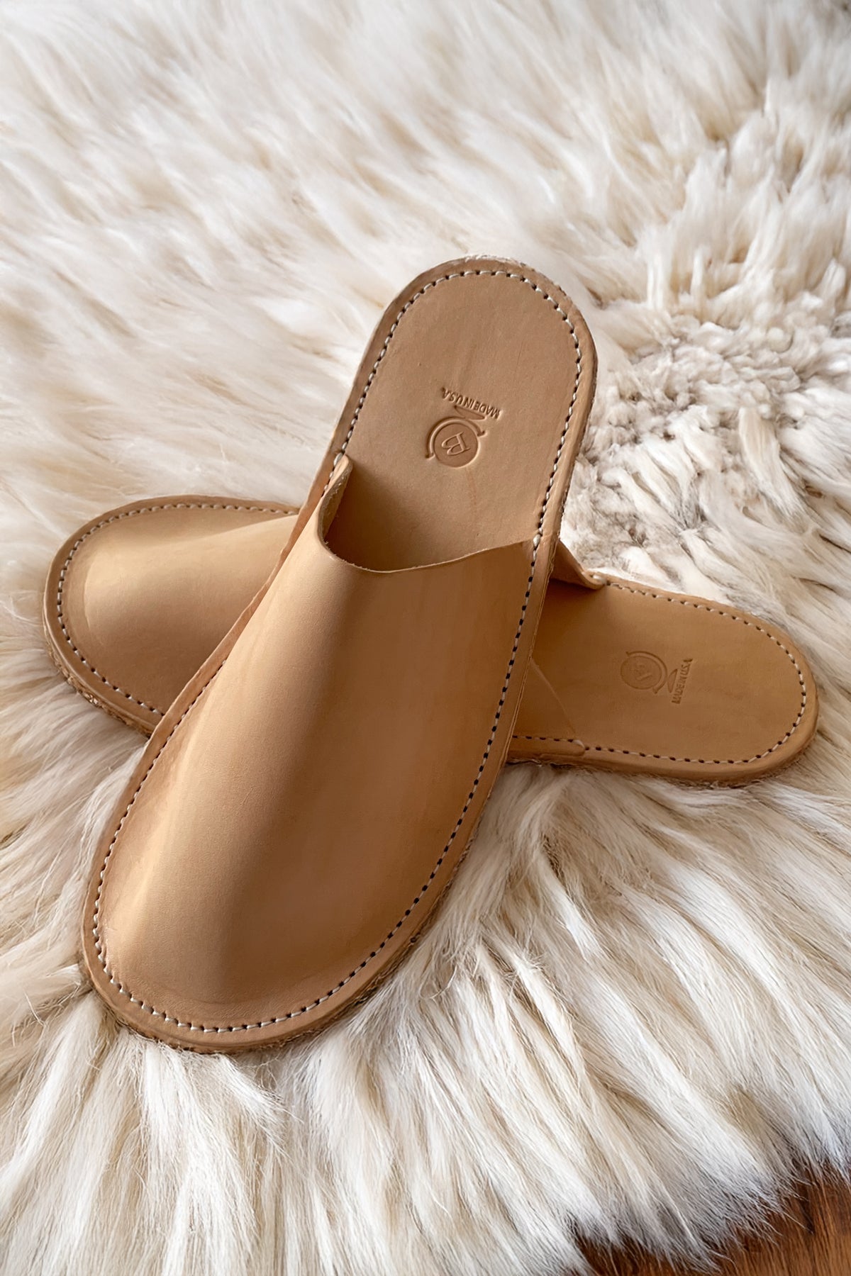 Sand leather-look slippers with open back, round toe, and visible stitching