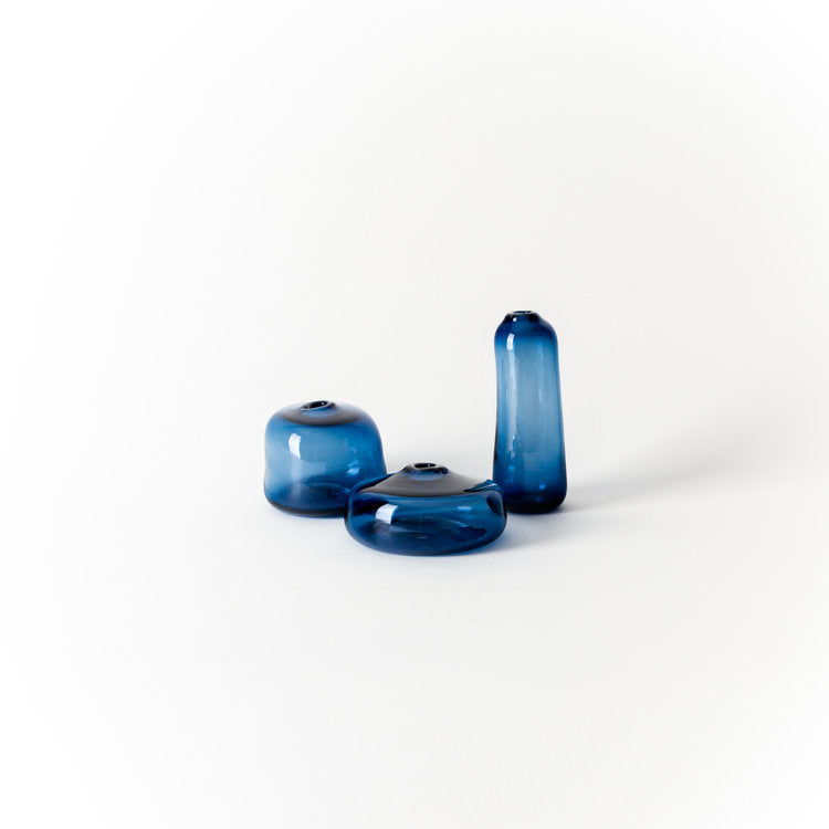 Set of three blue glass decorative vases, one tall and two short, rounded tops