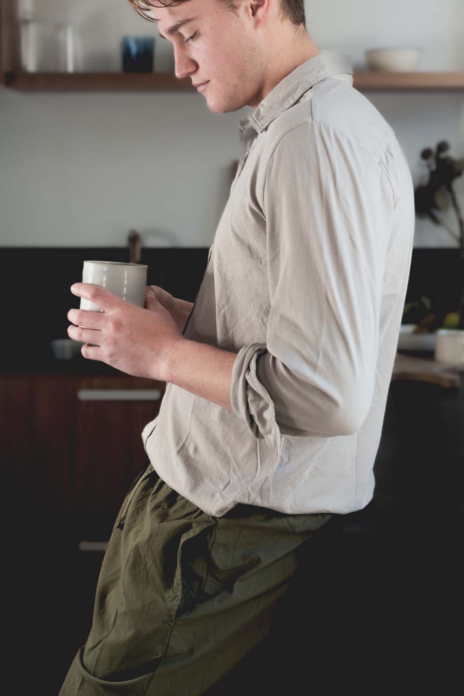 Stoneware mug held in hand, white body with beige base and curved handle
