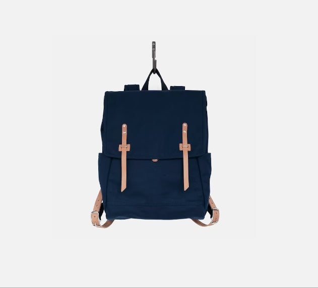 Dark blue canvas ruck sack with top flap and tan leather buckle straps